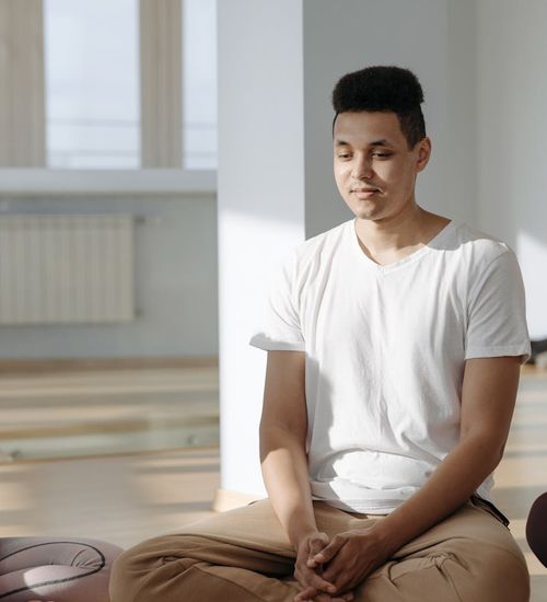 Person sitting in a calm meditation pose with light energy lines.